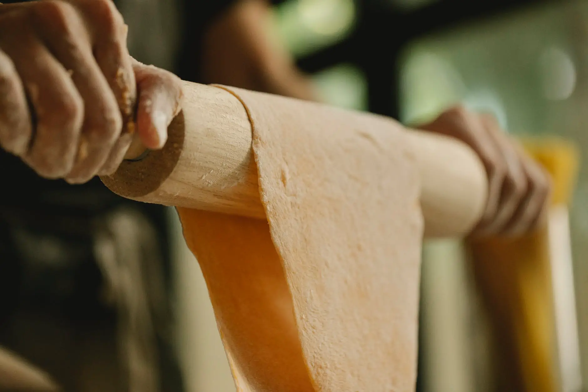 chef pulling sheet of dough on rolling pin
